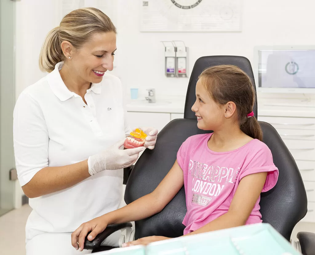 Dr Paula Göser explains an orthodontic appliance to a young patient in Cologne